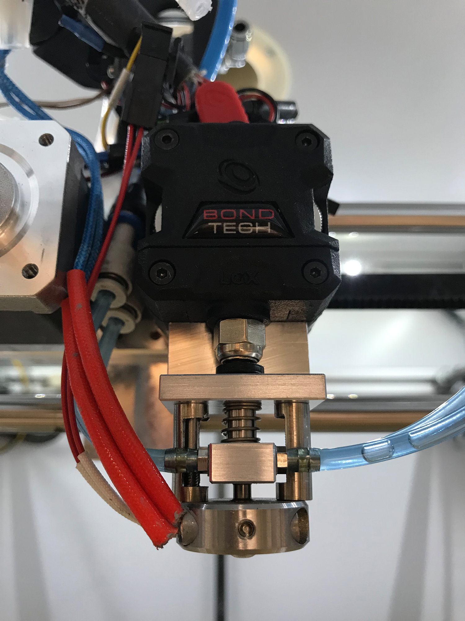 Prototyp einer Verschlussdüse für 3D-Drucker Ein kompaktes metallisches Bauteilin Nahaufnahme mit Schläuchen und Kabeln